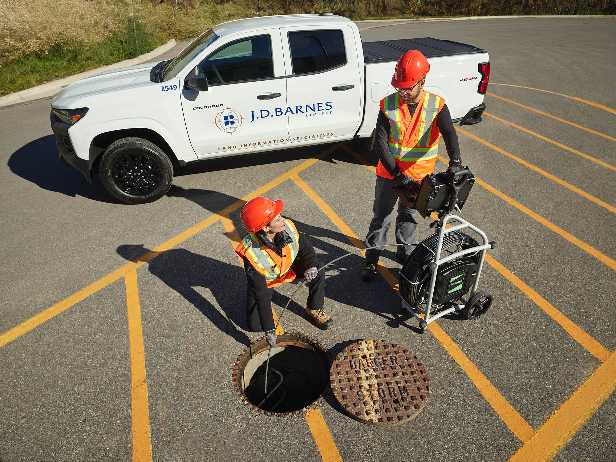 Two engineers using equipment to survey underground utilities.